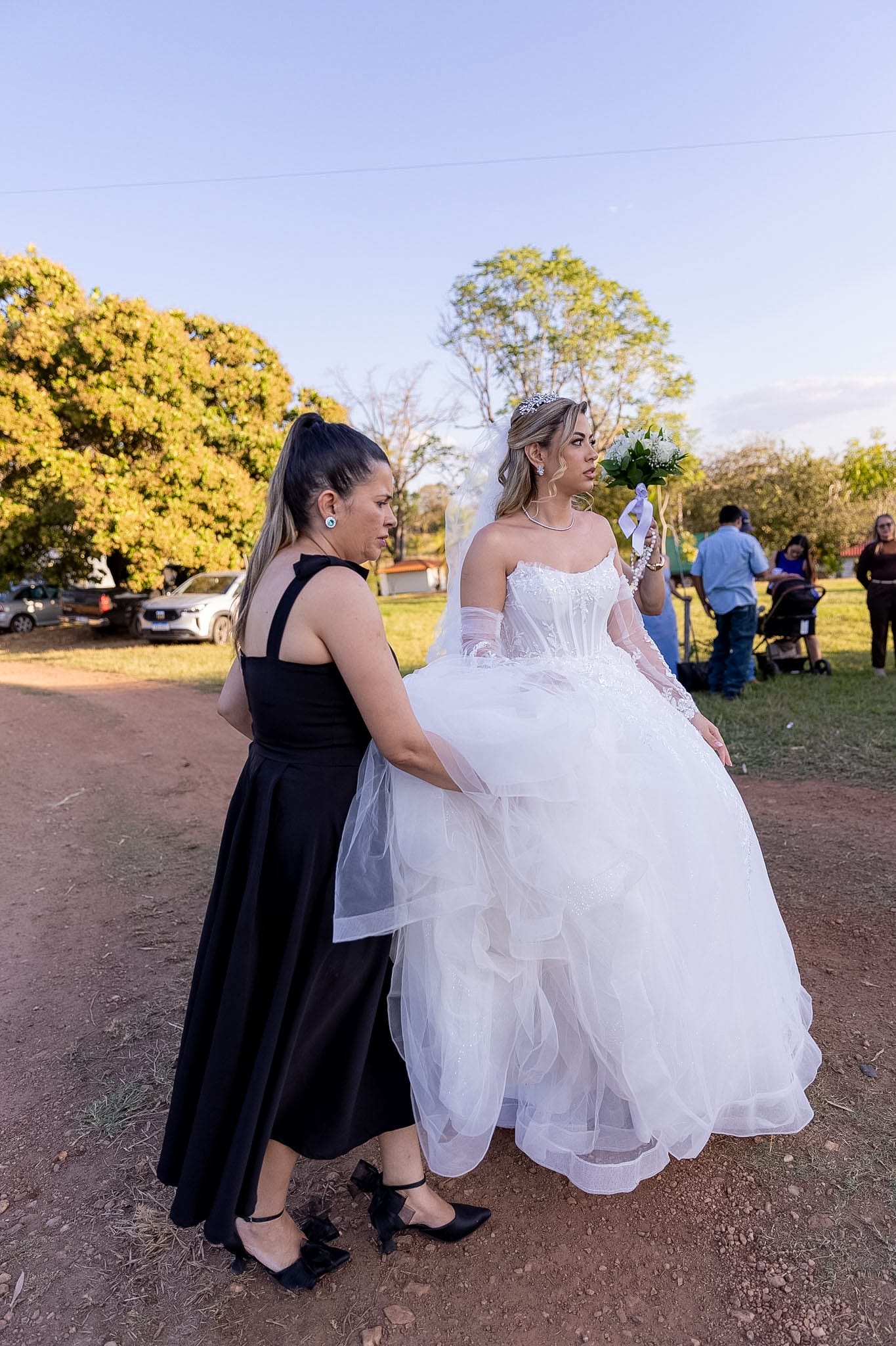 Weiri Borges ajeita o vestido da noiva ao ar livre, antes da cerimônia.